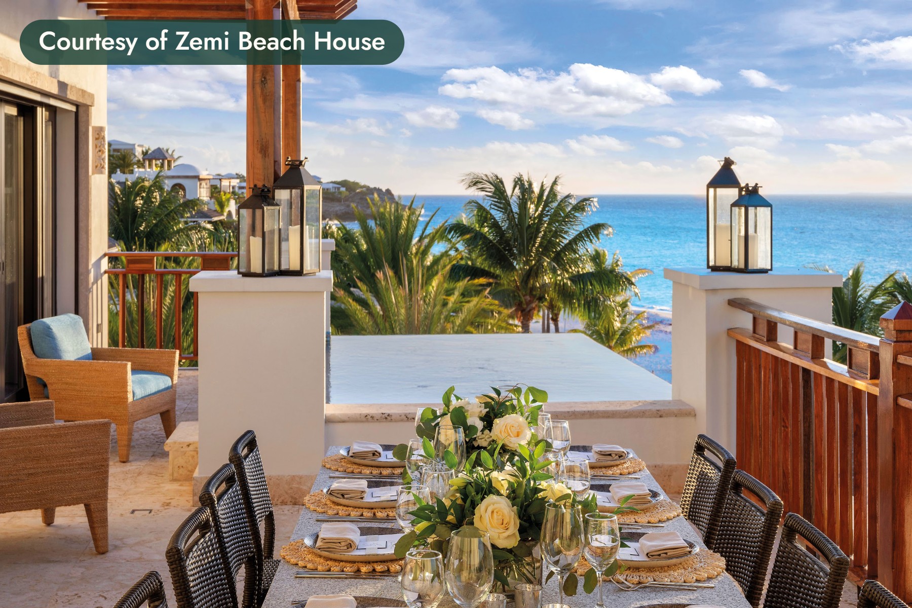 A dinner table set with roses and lanterns on a terrace above the sea in Anguilla. Courtesy of Zemi Beach House.
