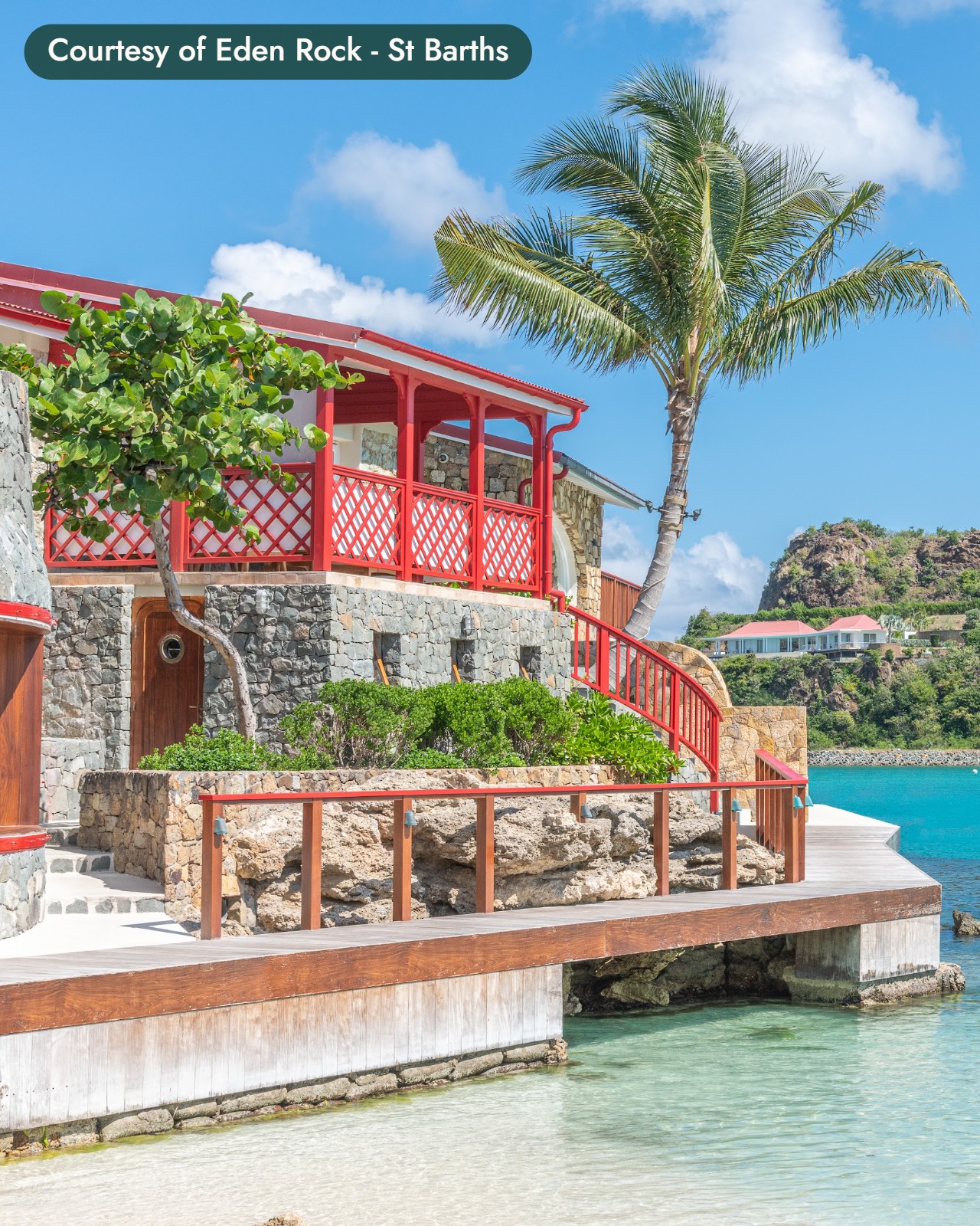 A red-trimmed villa and a palm on a rocky point above clear turquoise water in St. Barths. Courtesy of Eden Rock - St Barths.