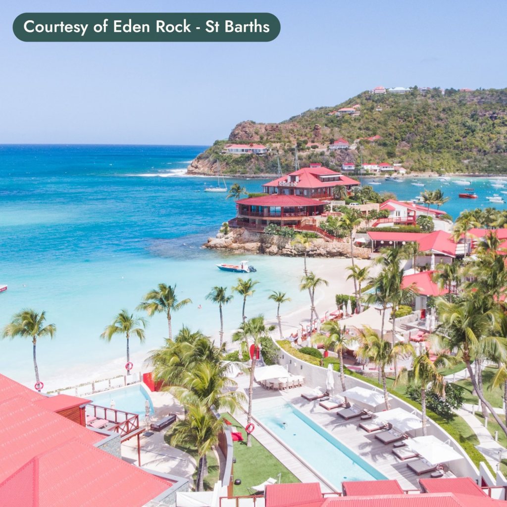 A beach resort with red roofs and palm trees on a turquoise bay in St. Barths. Courtesy of Eden Rock - St Barths.