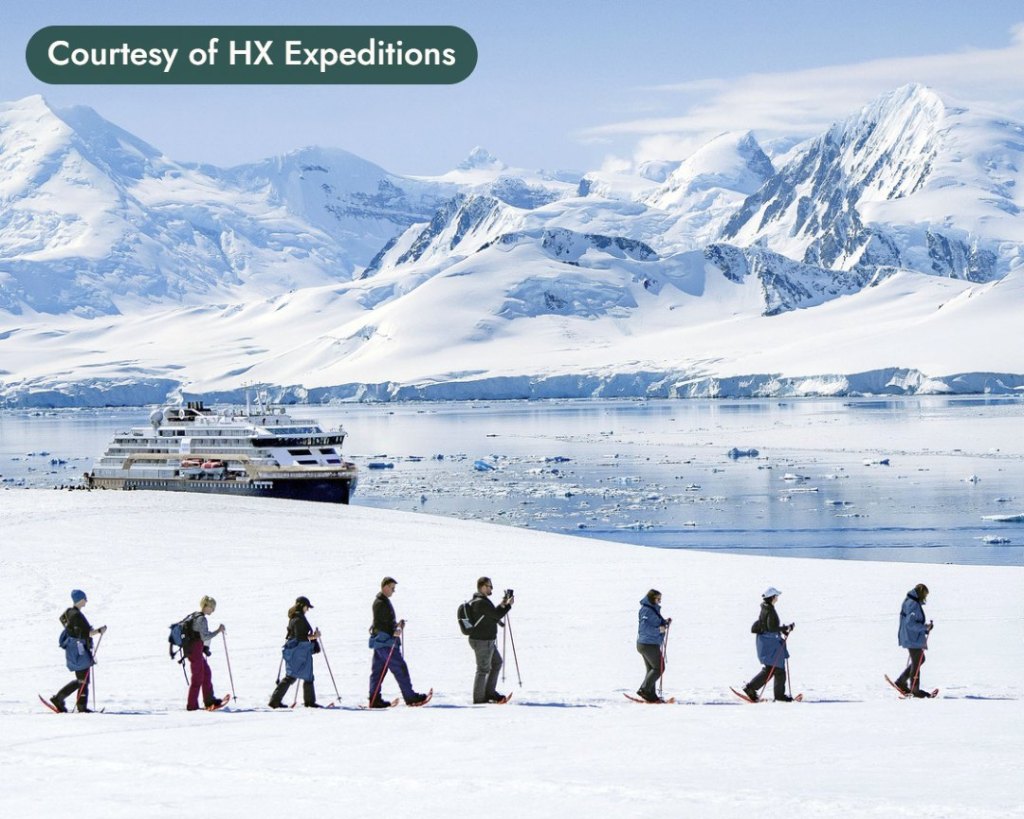 Small group snowshoeing, with an expedition ship and mountains behind. Courtesy of HX Expeditions.